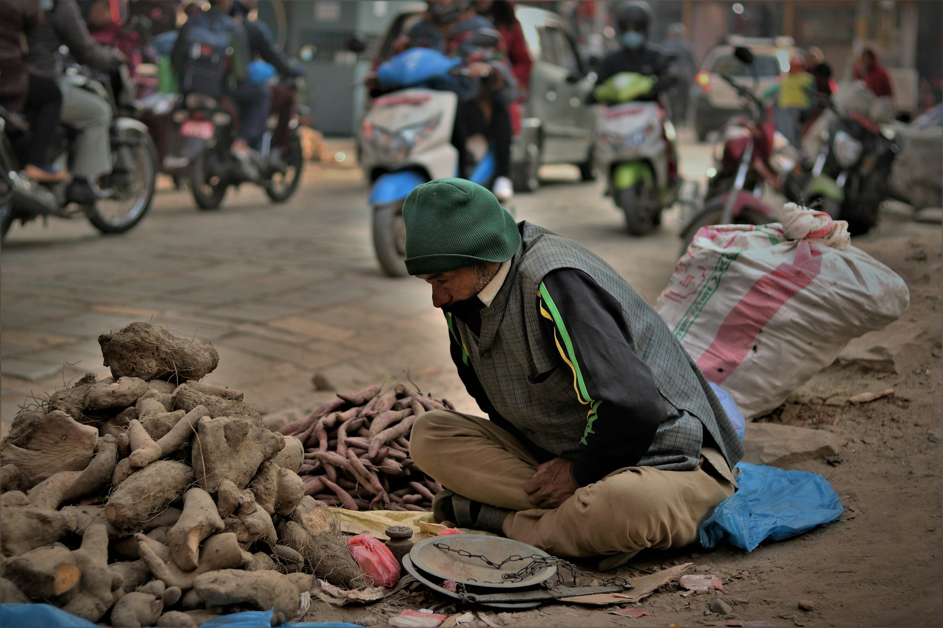सड़क के किनारे बैठे आदमी की उथली फ़ोकस वाली तस्वीर